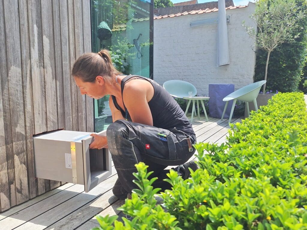 Un installateur installe une chatière dans le mur extérieur revêtu de bois d'une maison moderne - Tomsgates Nipper (S)